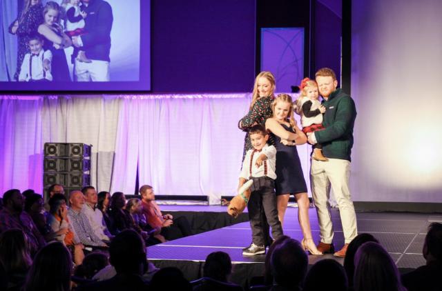 Kinley in the Fashow Show posing with Corbin, another BuckeyeThon Kids, his sister Lily, and our models.